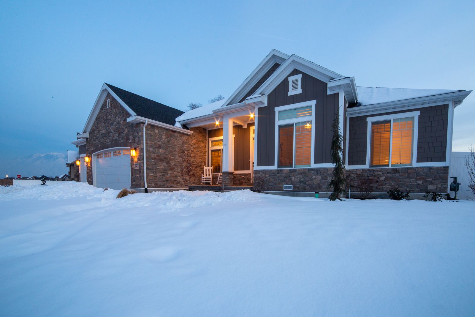Home with bright exterior lighting on a snowy evening