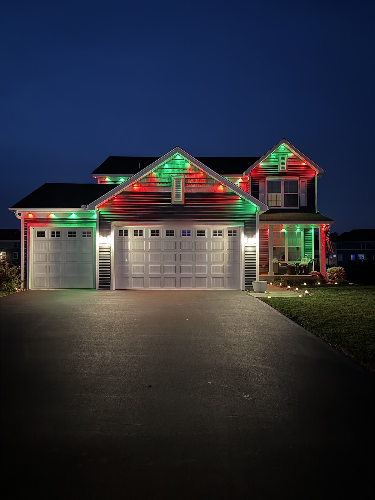 Two-story house in red and green lights at dusk